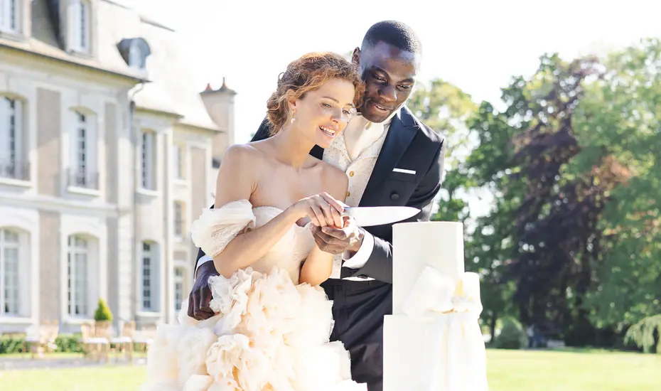 The couple sharing the first slice of cake in front of the chateau