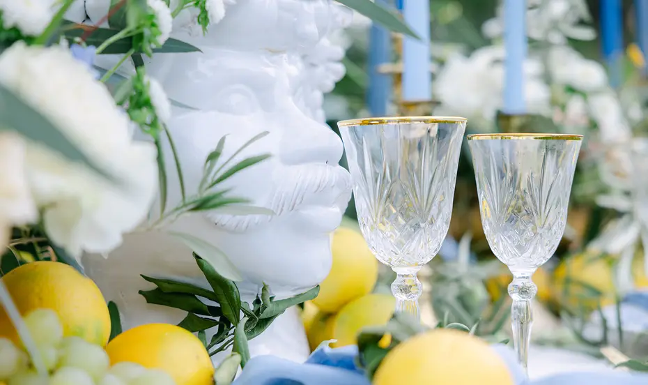 Two cut crystal glasses set beside the lemons and foliage of a table setting