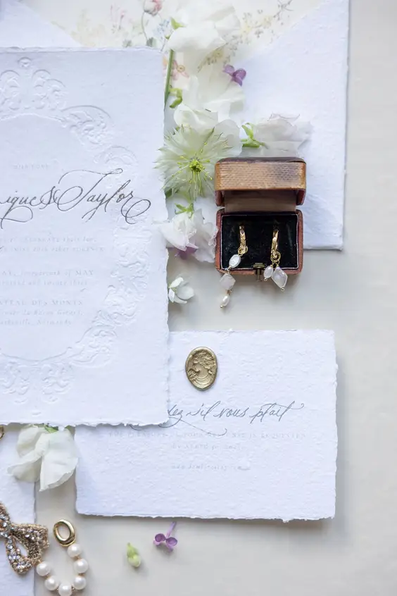 A stationery flat lay: invitation suite, envelope and ribbon.