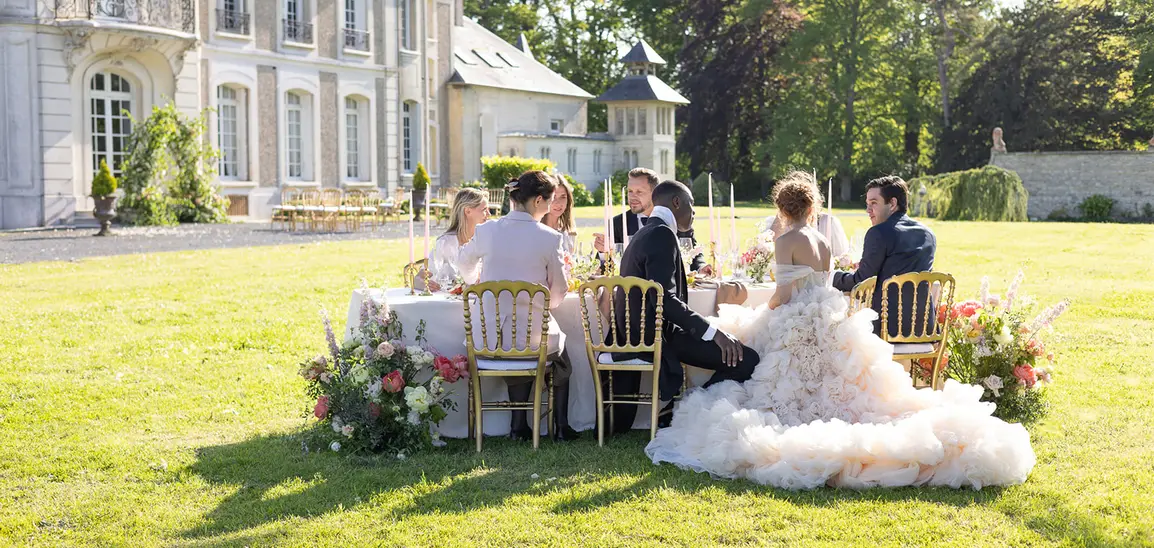 Guests gathered around a long table on the lawn of the château.
