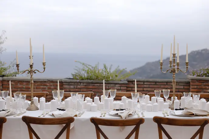A long dinner table set on a terrace above the château gardens.