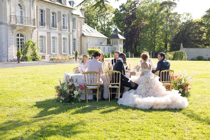 Guests gathered on the lawn of the château at golden hour.