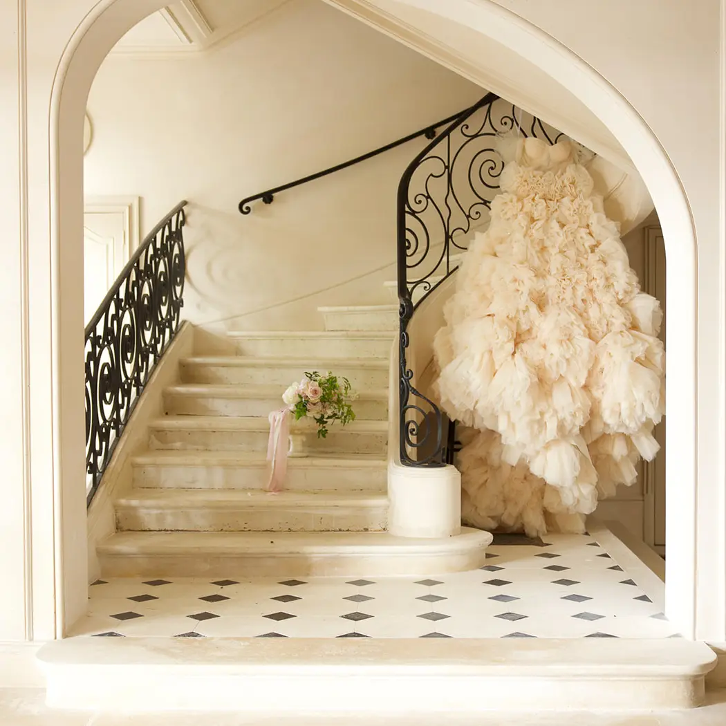 A curved stone staircase inside Château Diter, white tulle draped along the wrought-iron railing.